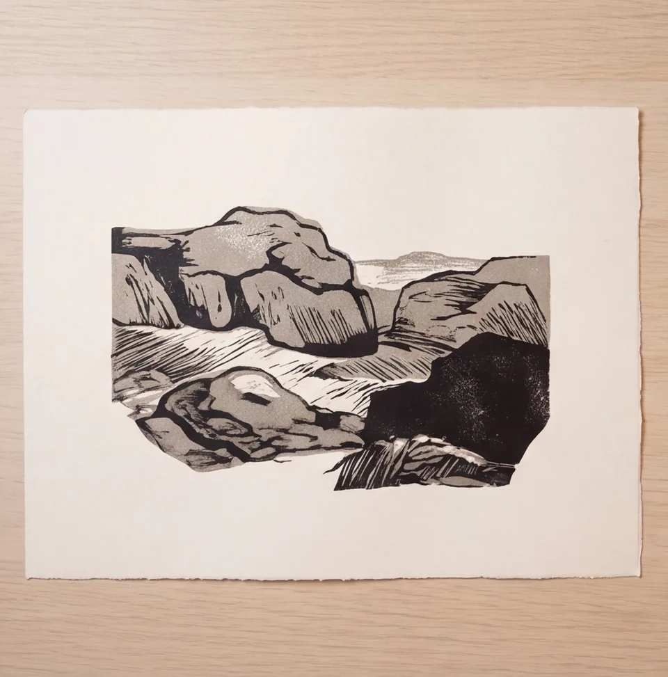 A linocut print of coastal rocks